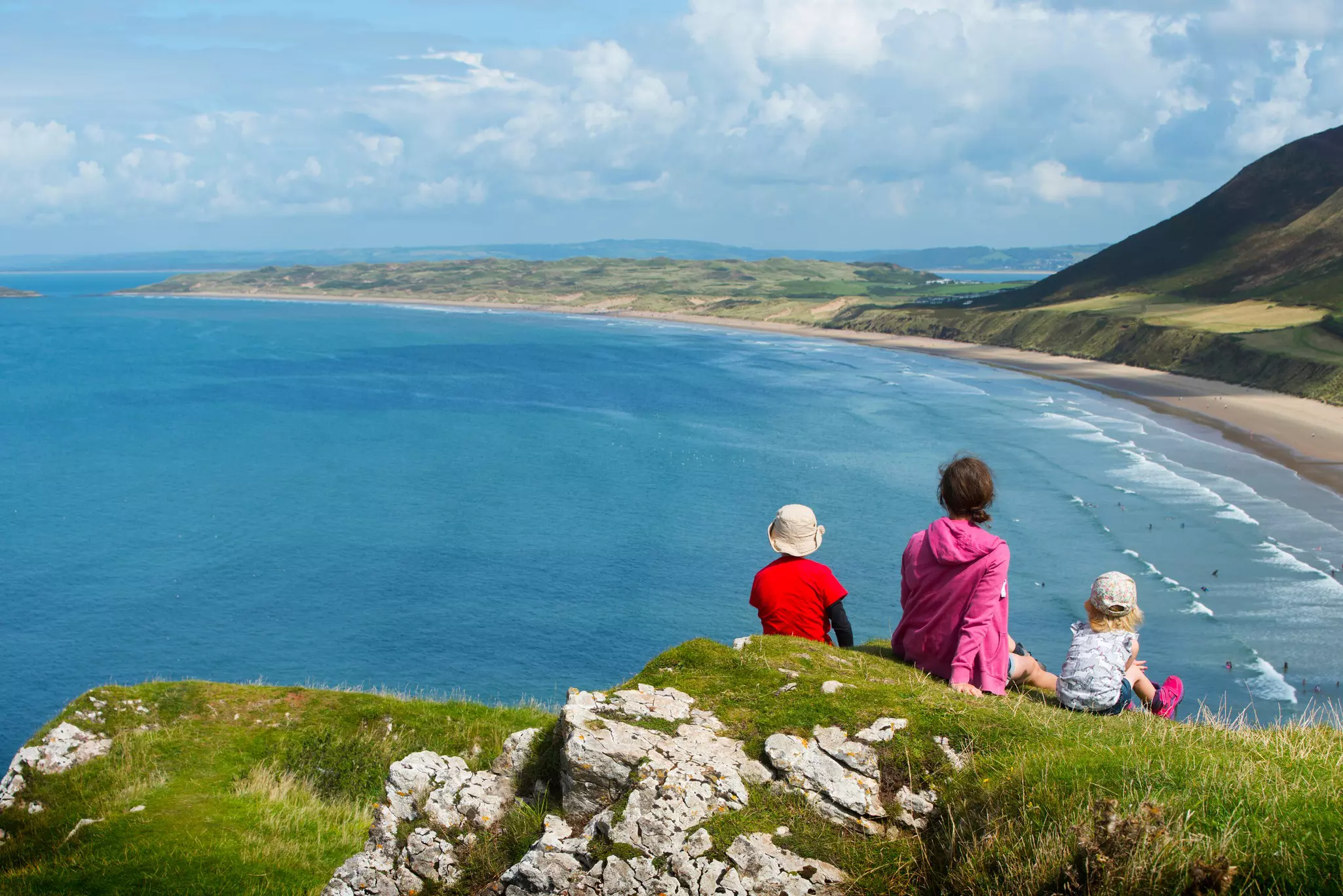 A family on the clifftop looking over Rhossili Bay on The Gower, South Wales.