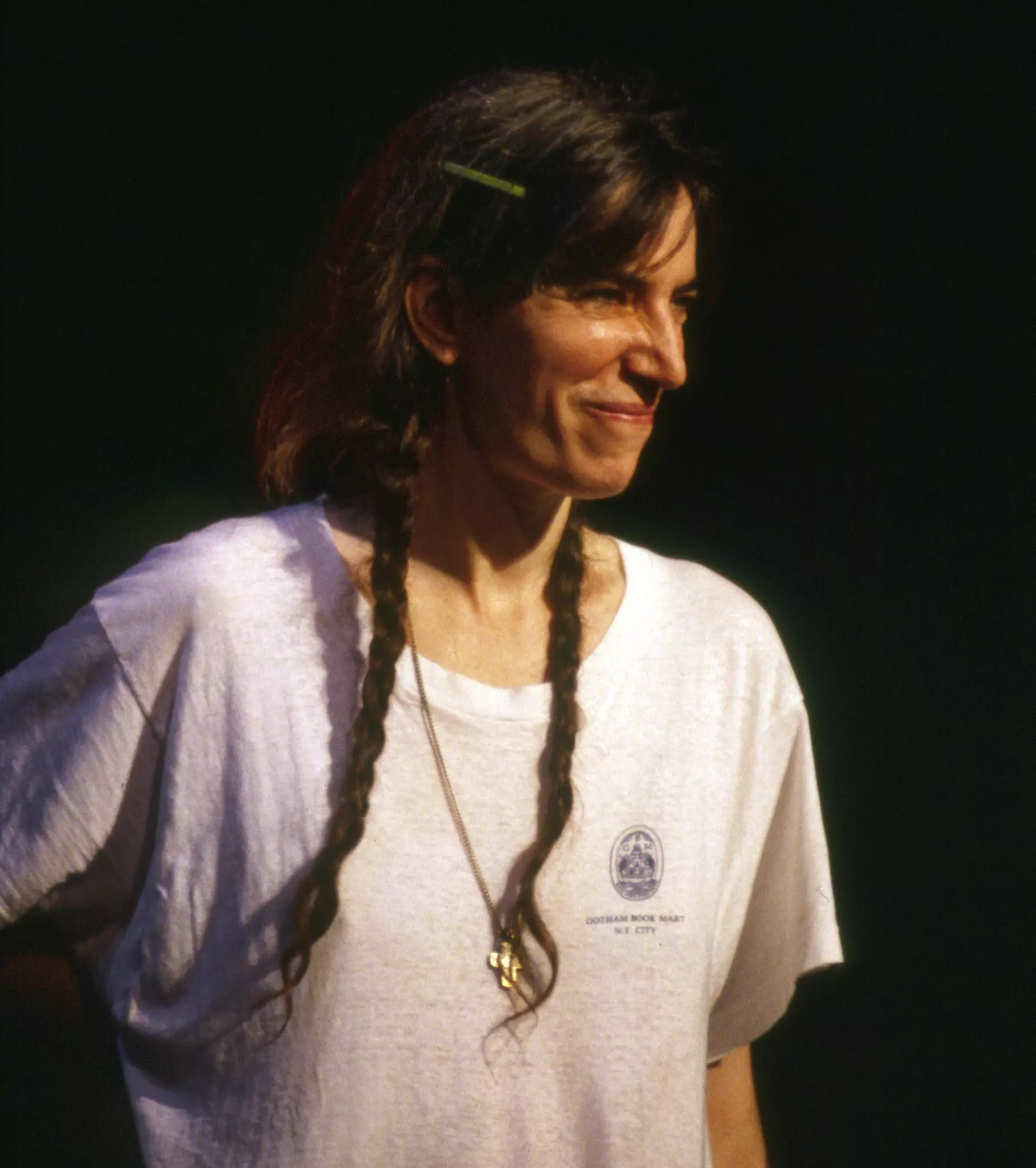 Close up of a woman with long brown hair smiles while wearing a white tshirt