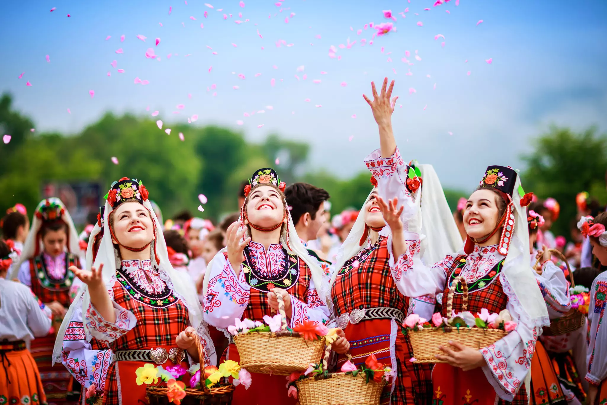 Four Bulgarian girls dressed in traditional clothing throwing rose petals in the air during the Annual Rose Festival in Kazanlâk, Bulgaria.