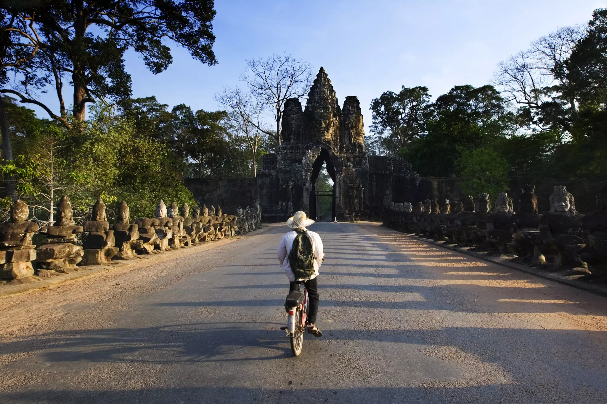 A cyclist approaches the carved gateway to a temple at Angkor in Cambodia.