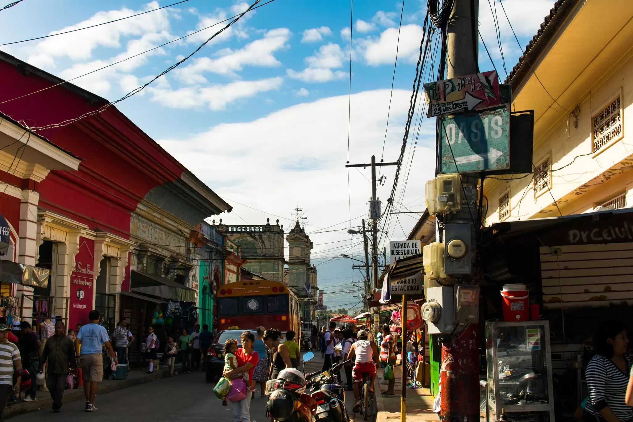 People walk past vendors selling assorted products on a street in Granada, Nicaragua.