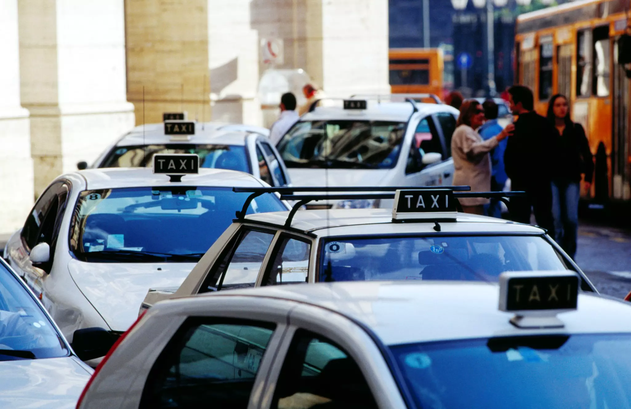 A taxi stand with white cars parked in a line.