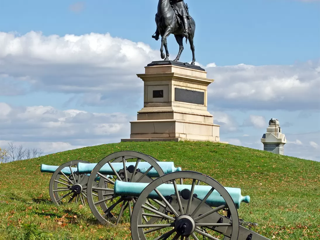 A Gettysburg statue with military wagons in the forefront