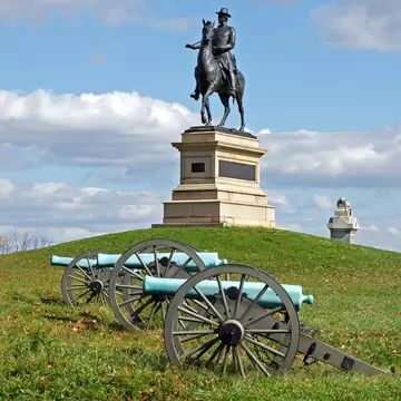 A Gettysburg statue with military wagons in the forefront