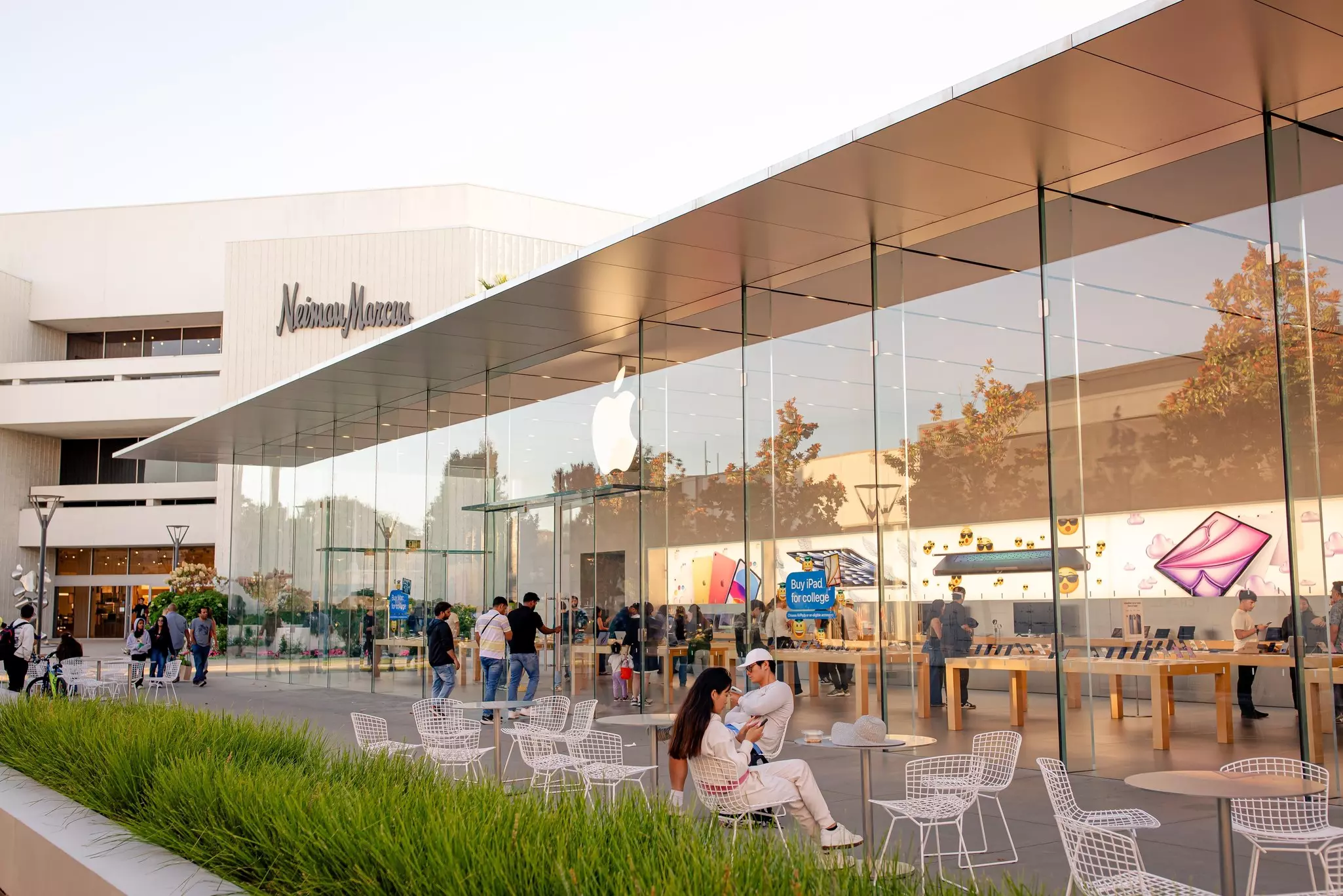 People sitting at tables in an outdoor shopping center.