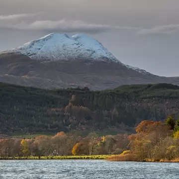 Looking across Loch Ard in the Scottish Highlands to the snowy summit of Ben Lomond, Loch Lomond & The Trossachs National Park, Scotland.