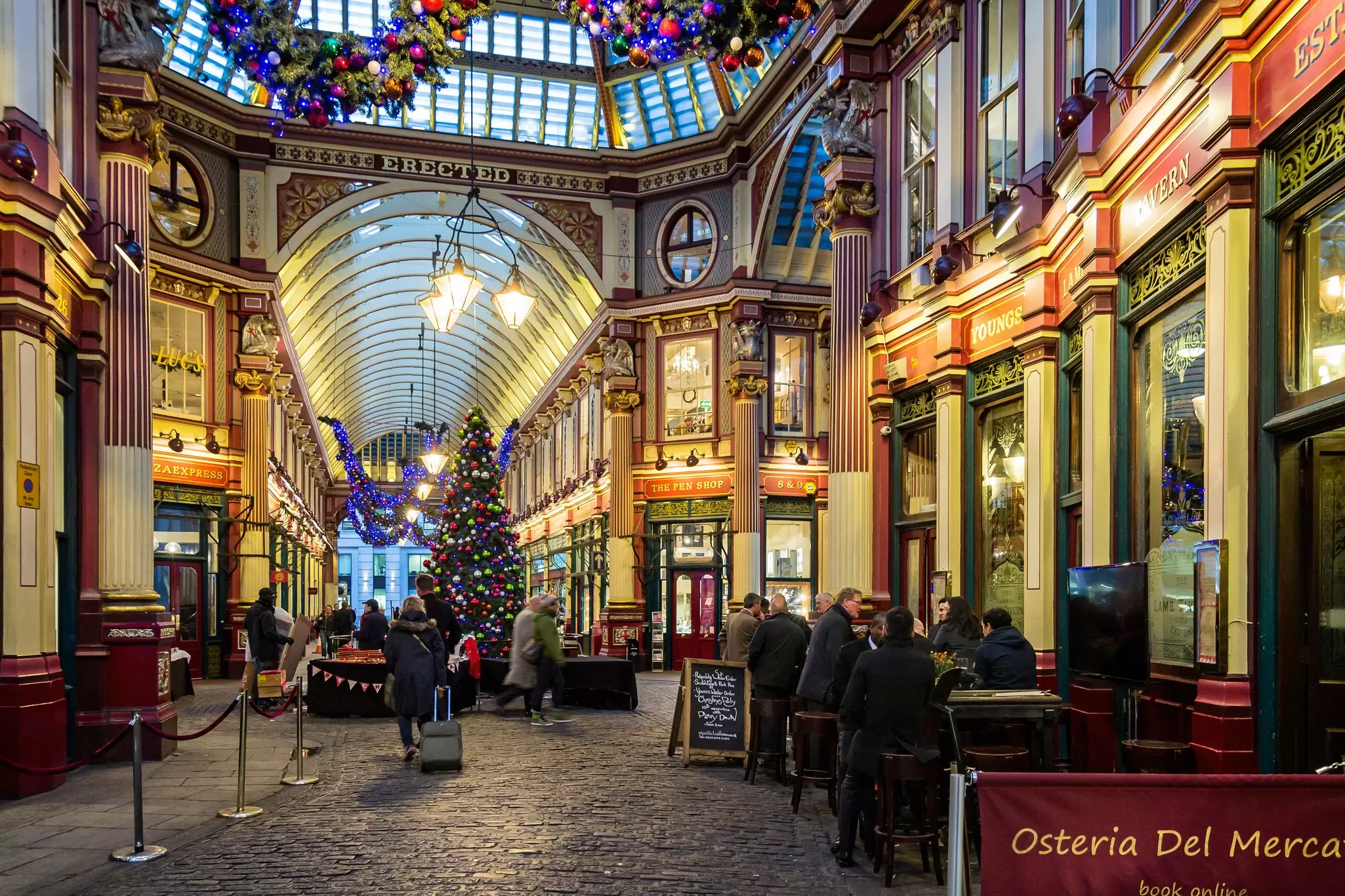 Leadenhall Market bars and shops lit up with Christmas decorations and a Christmas tree