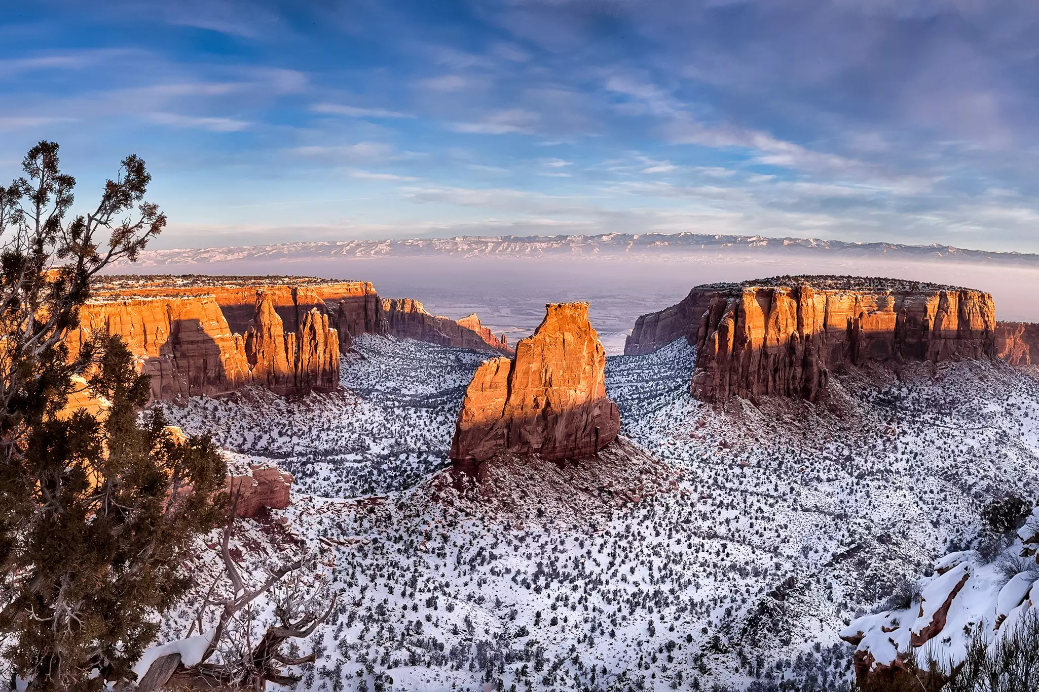 Sunshine glints off rocky outcrops iwith a dusting of snow on the ground below..