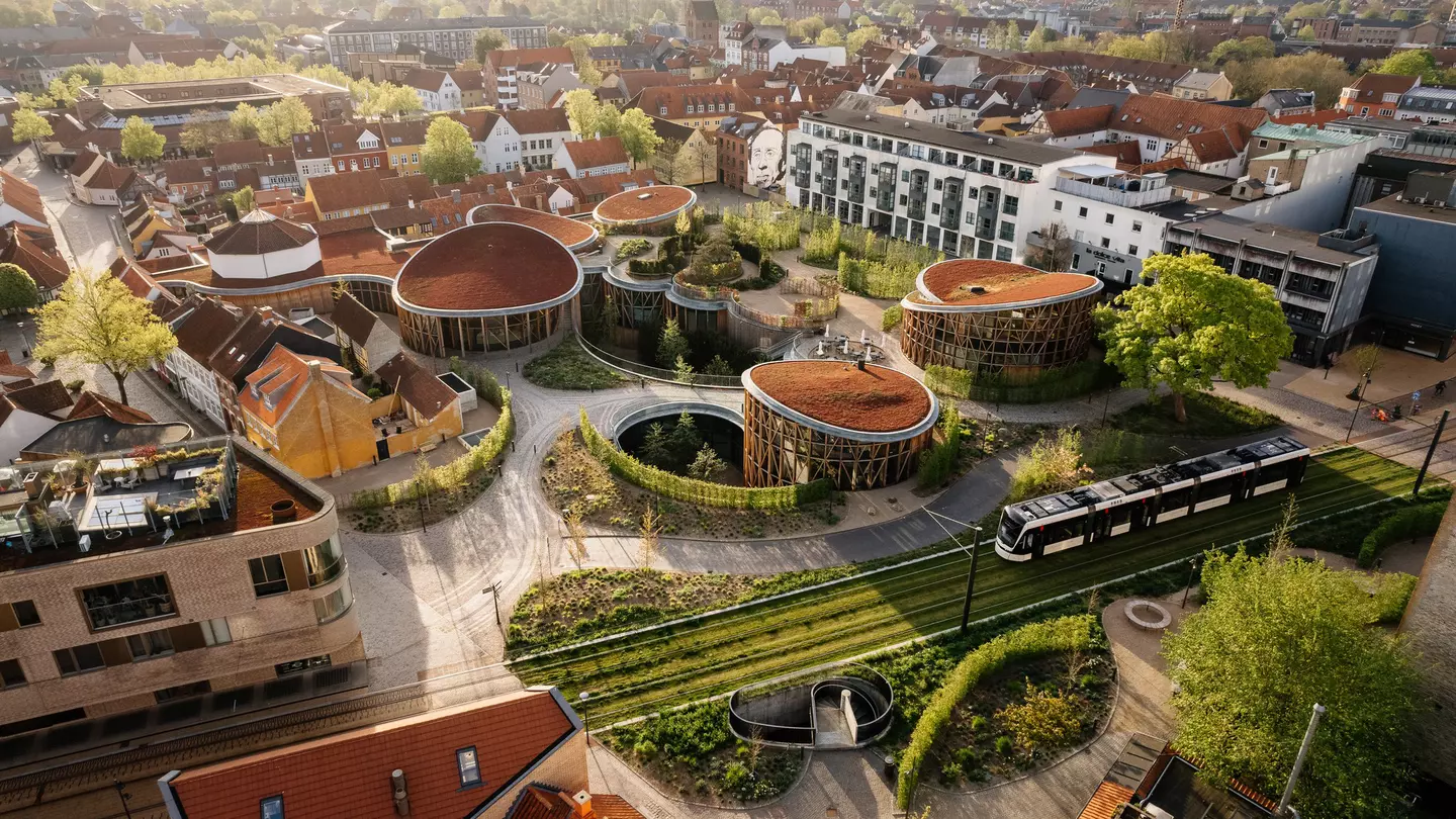 An overhead view of a museum with gardens and numerous pavilions in a city. A tram passes the museum, while apartment buildings surround the complex.