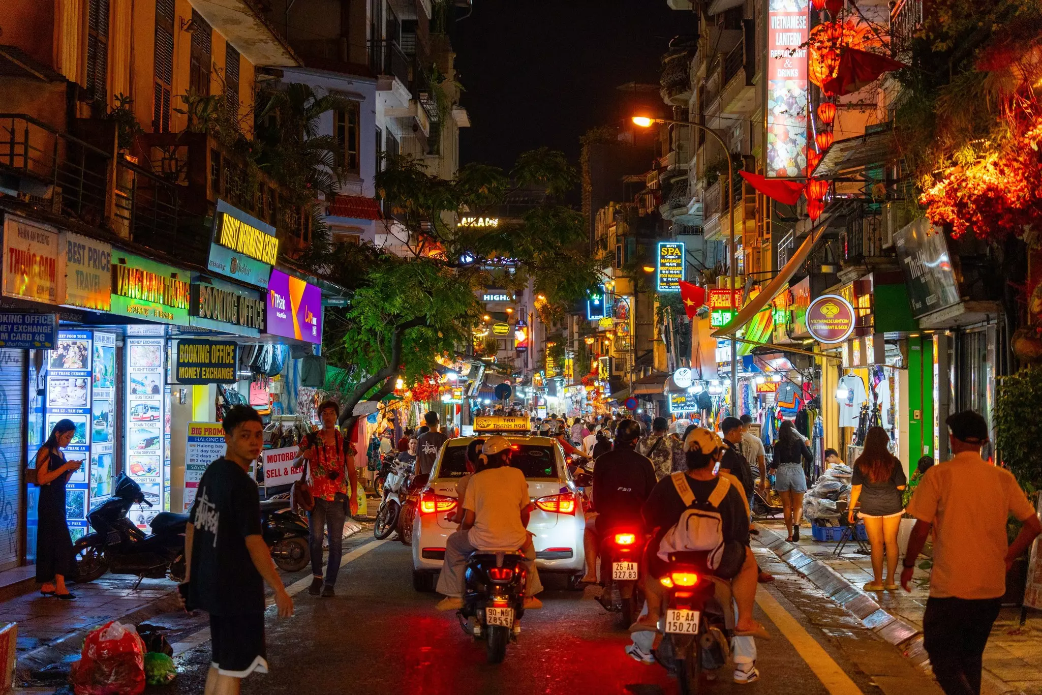 A night view of Hanoi Old Quarter Beer Street with pedestrians, bikers and lit-up shops