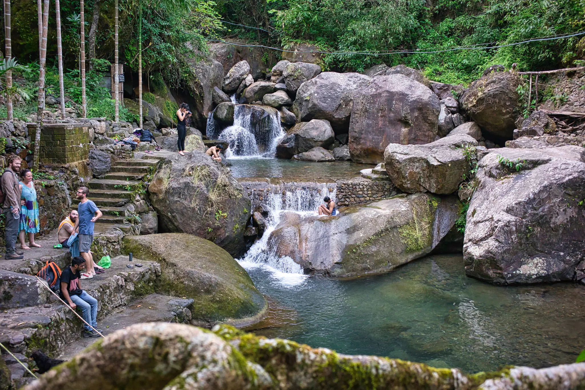 Swimmers in a plunge pool fed by small waterfalls.