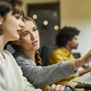 Coworkers discussing over computer in office