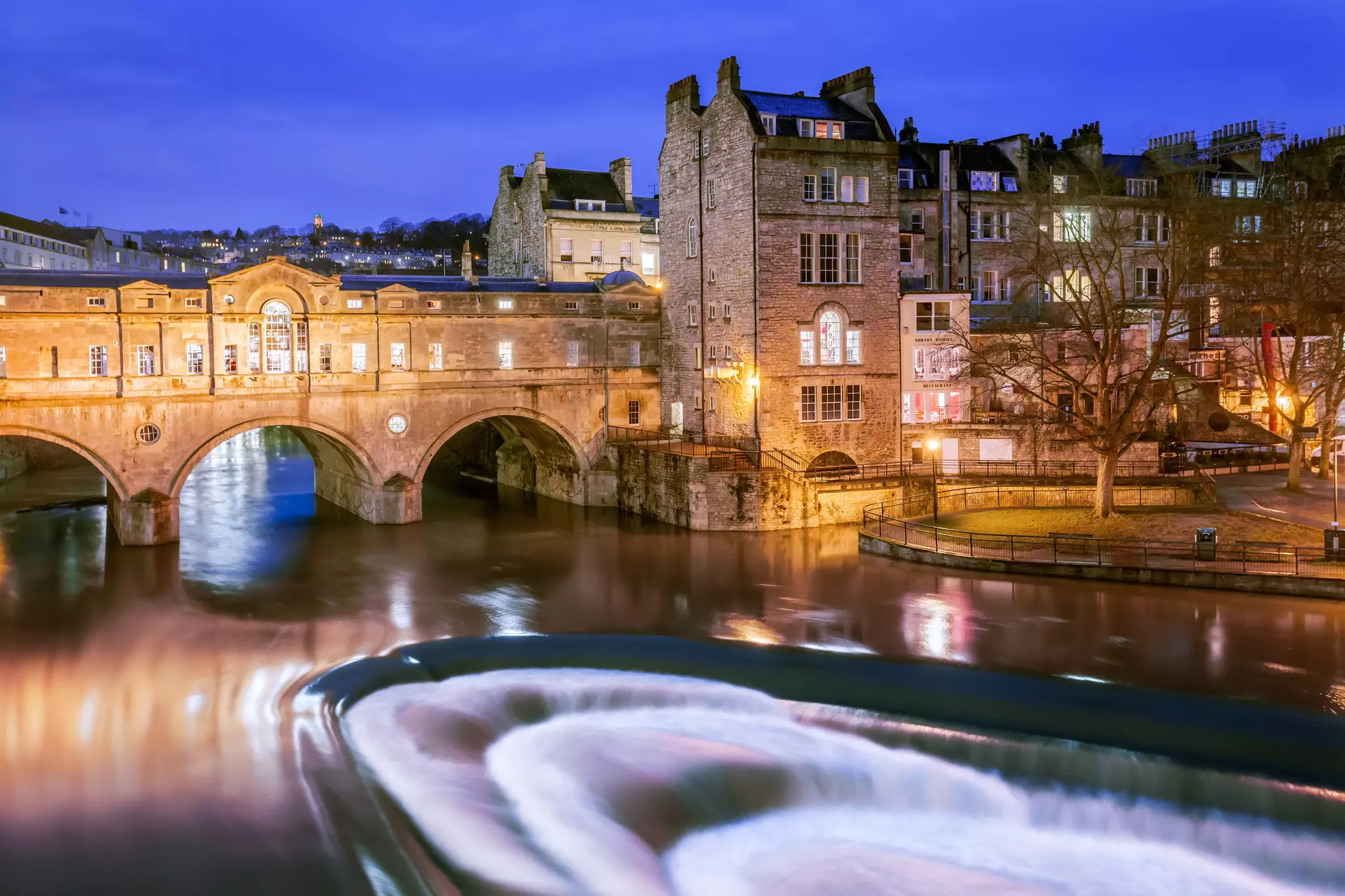 A Georgian bridge crosses a fast flowing river in the evening
