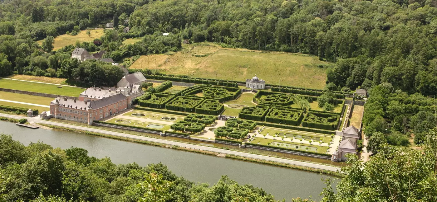 Aerial view of Château de Freÿr, showing the baroque castle with its formal French gardens with its geometric layouts and manicured grounds along the Meuse River.