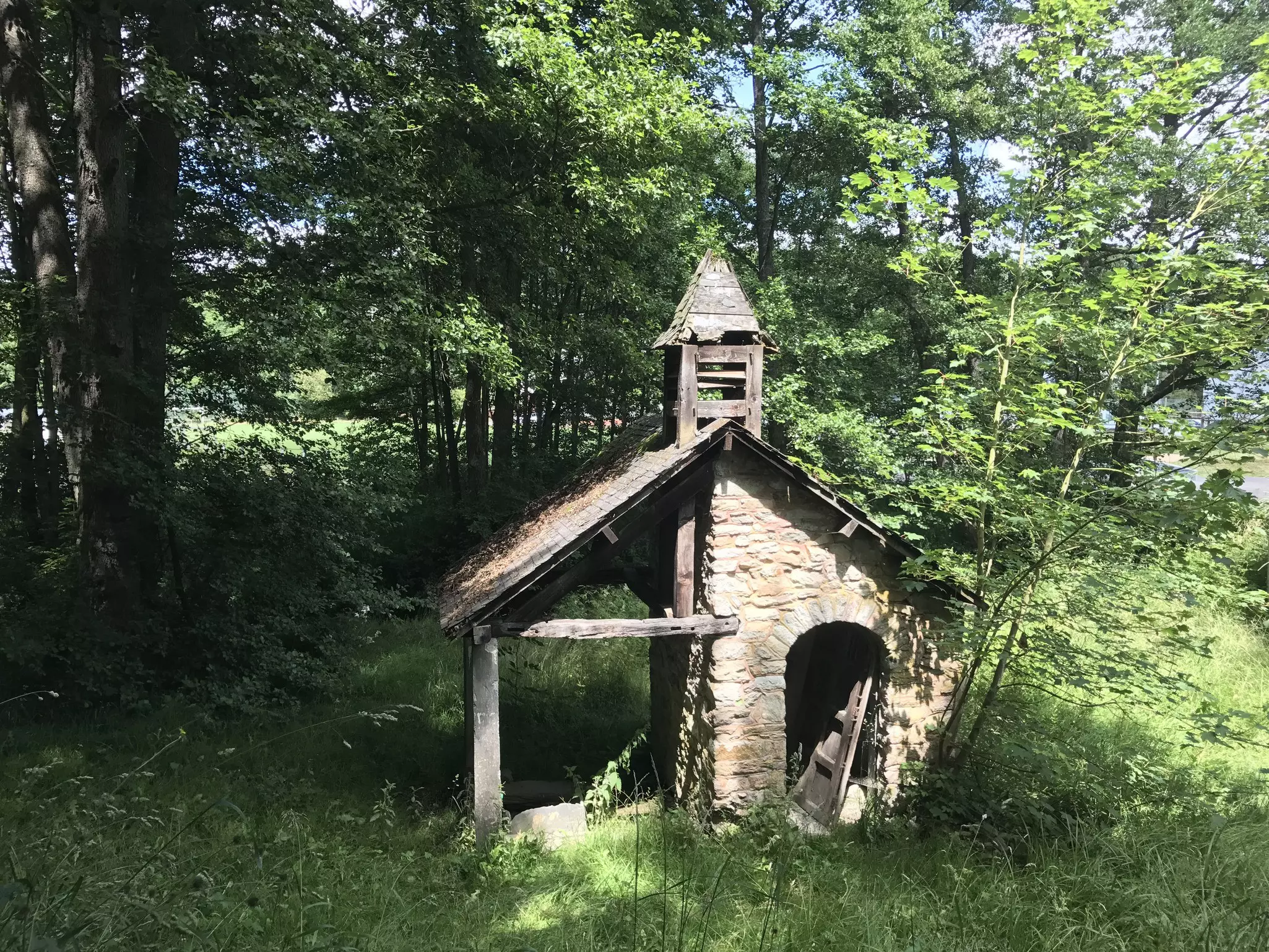 Small abandone stone house in the middle of a forest on a sunny day.