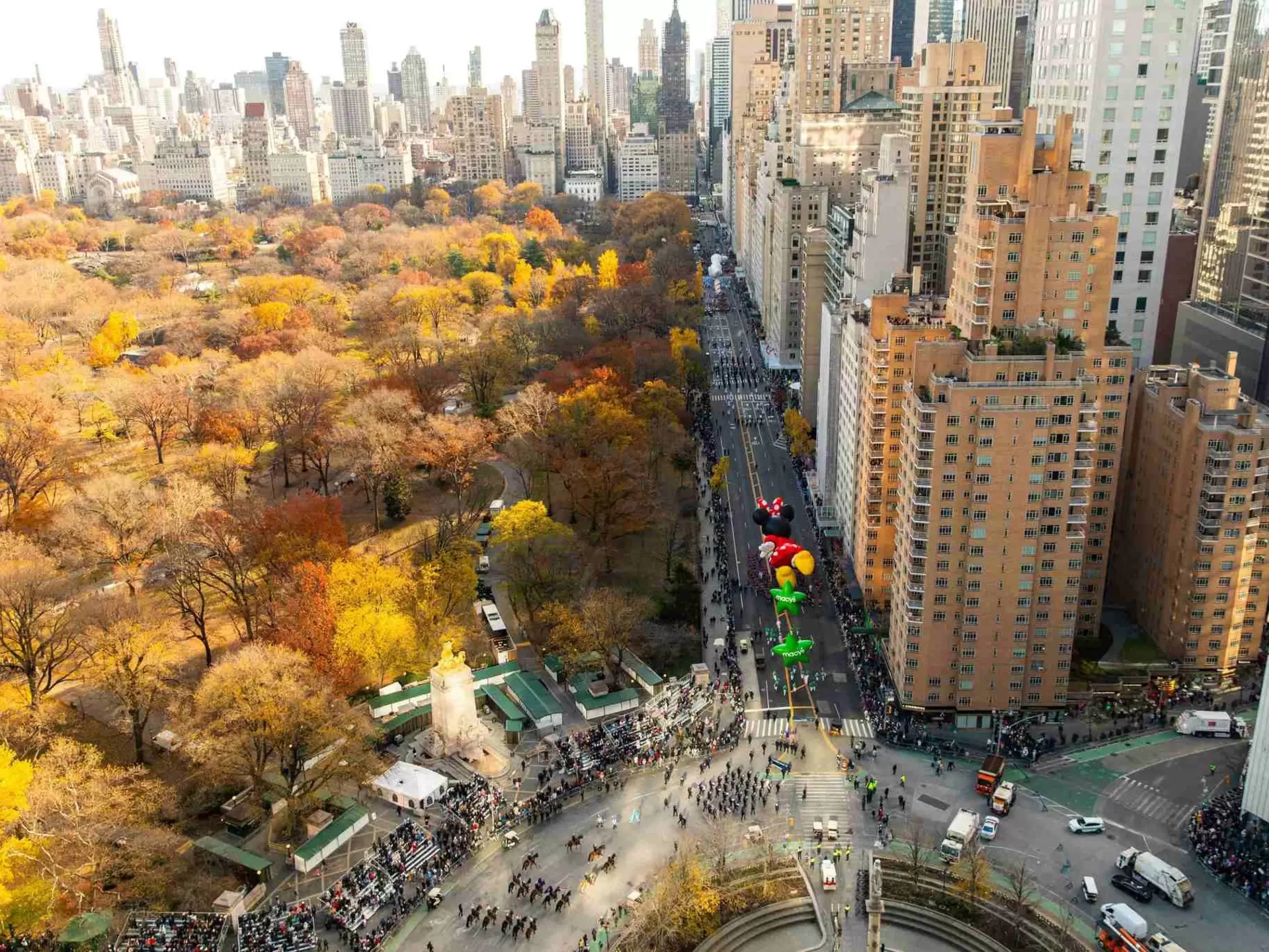City streets and a vast park stretch out below in a view from a high-rise hotel. Large cartoon-character balloons are carried down the street in a parade. Views of The Macy’s Thanksgiving Day Parade from above. Mandarin Oriental, New York