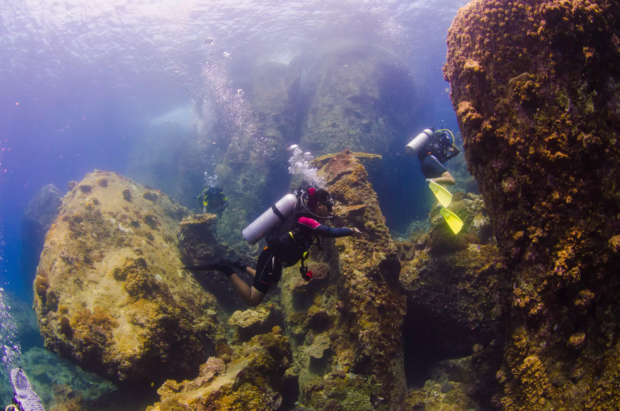 Two people diving underwater with giant boulders