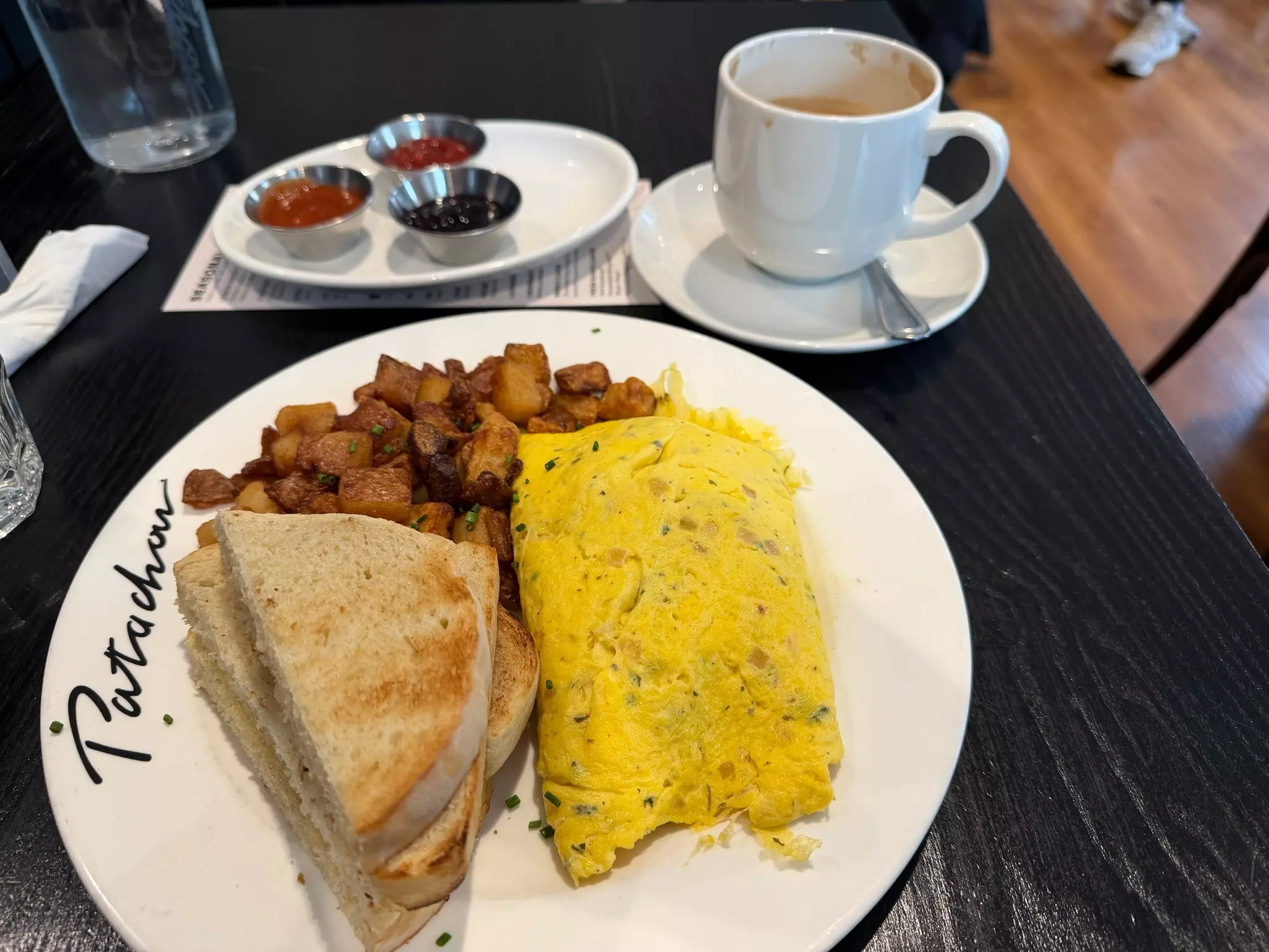 A plate with toast, eggs and roasted potatoes. In the background there's cup of chai.