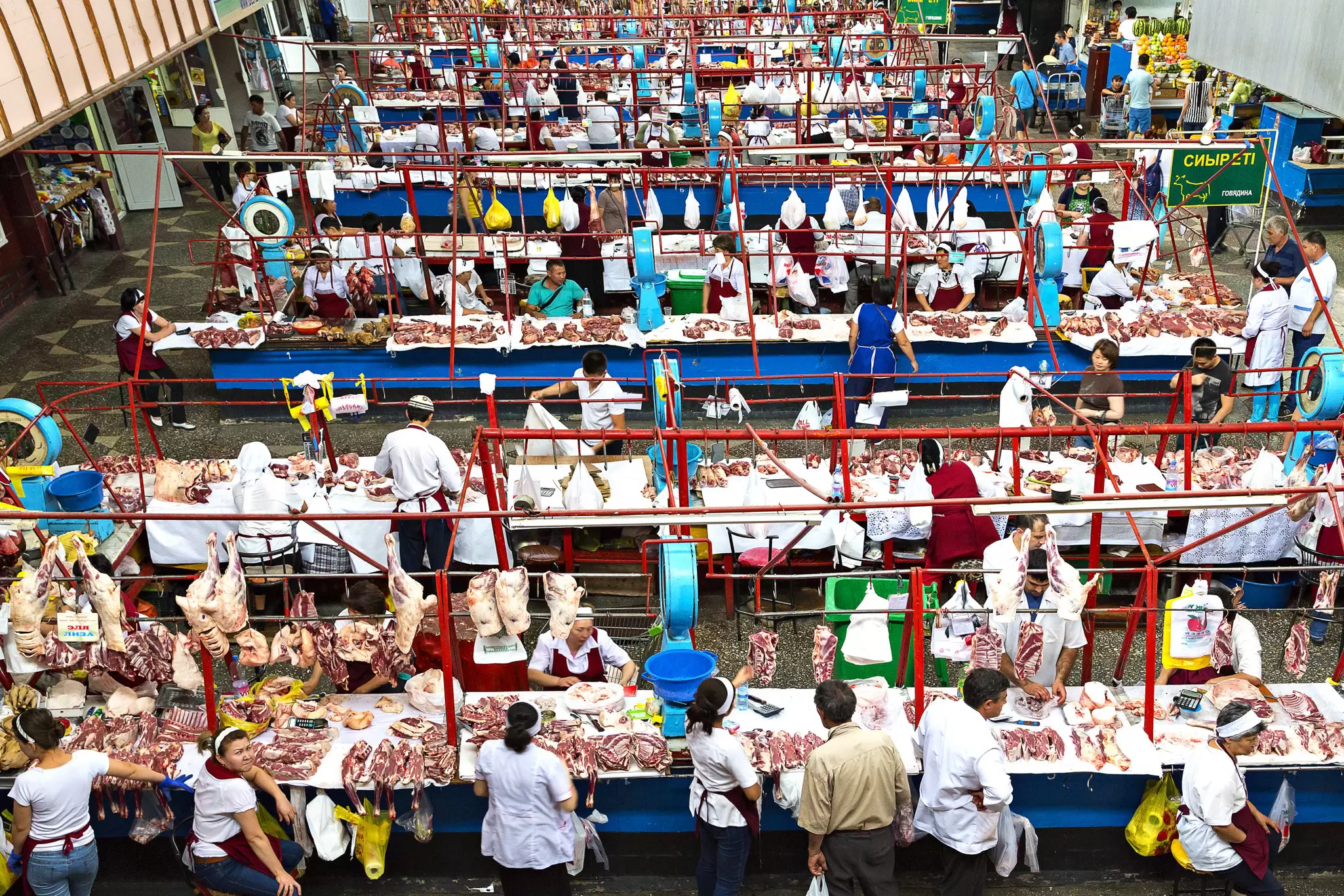 A wide shot of dozens of vendors in a covered market selling cuts of meat, Almaty, Kazakhstan