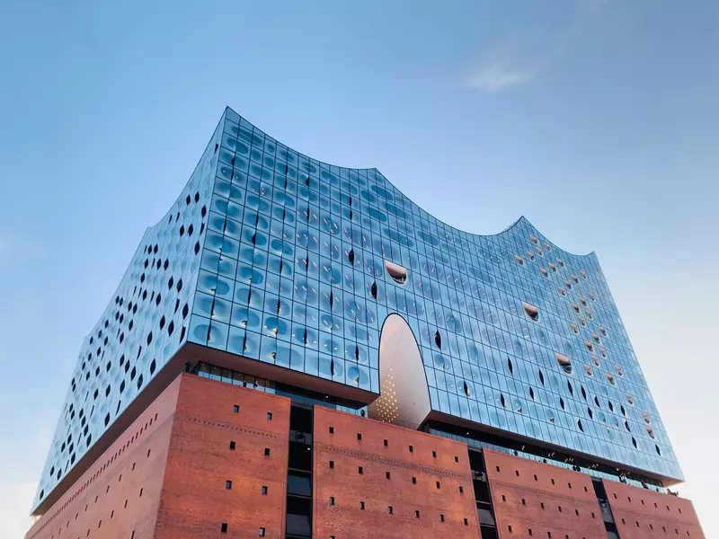 A modern building with brick at the base and curved glass above.