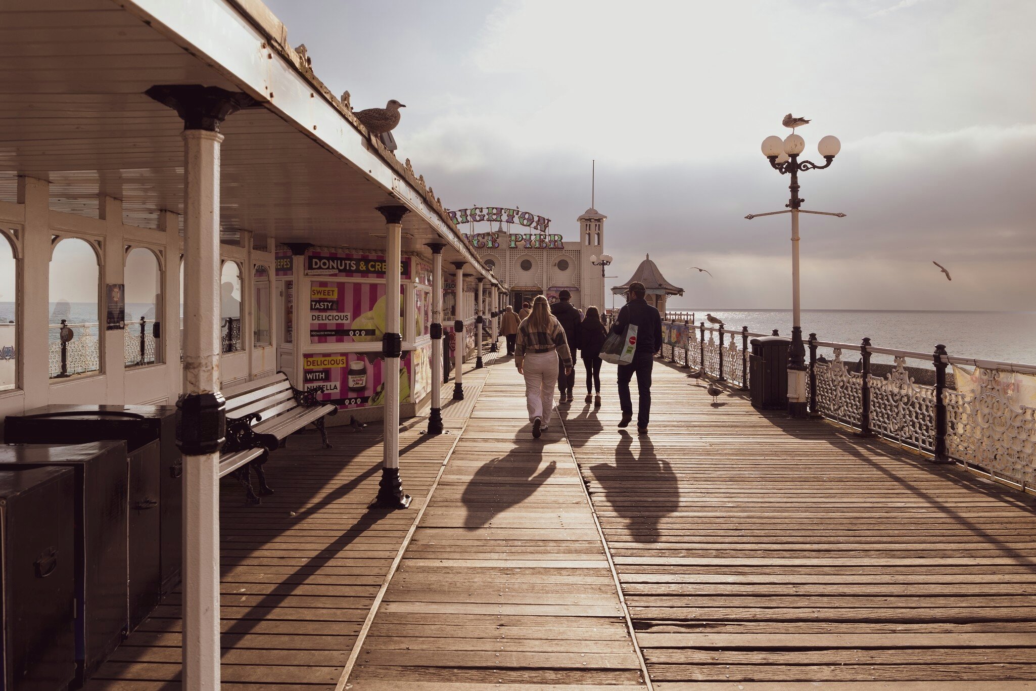 Brighton, East Sussex, United Kingdom - November 4th 2024: People walking on Brighton pier in golden autumn light. Brighton is a seaside resort on the south coast of England, License Type: media, Download Time: 2025-02-03T15:47:55.000Z, User: sashabrady26, Editorial: true, purchase_order: 65050 - Digital Destinations and Articles, job: Lonely Planet, client: Photo haul, other: Sasha Brady