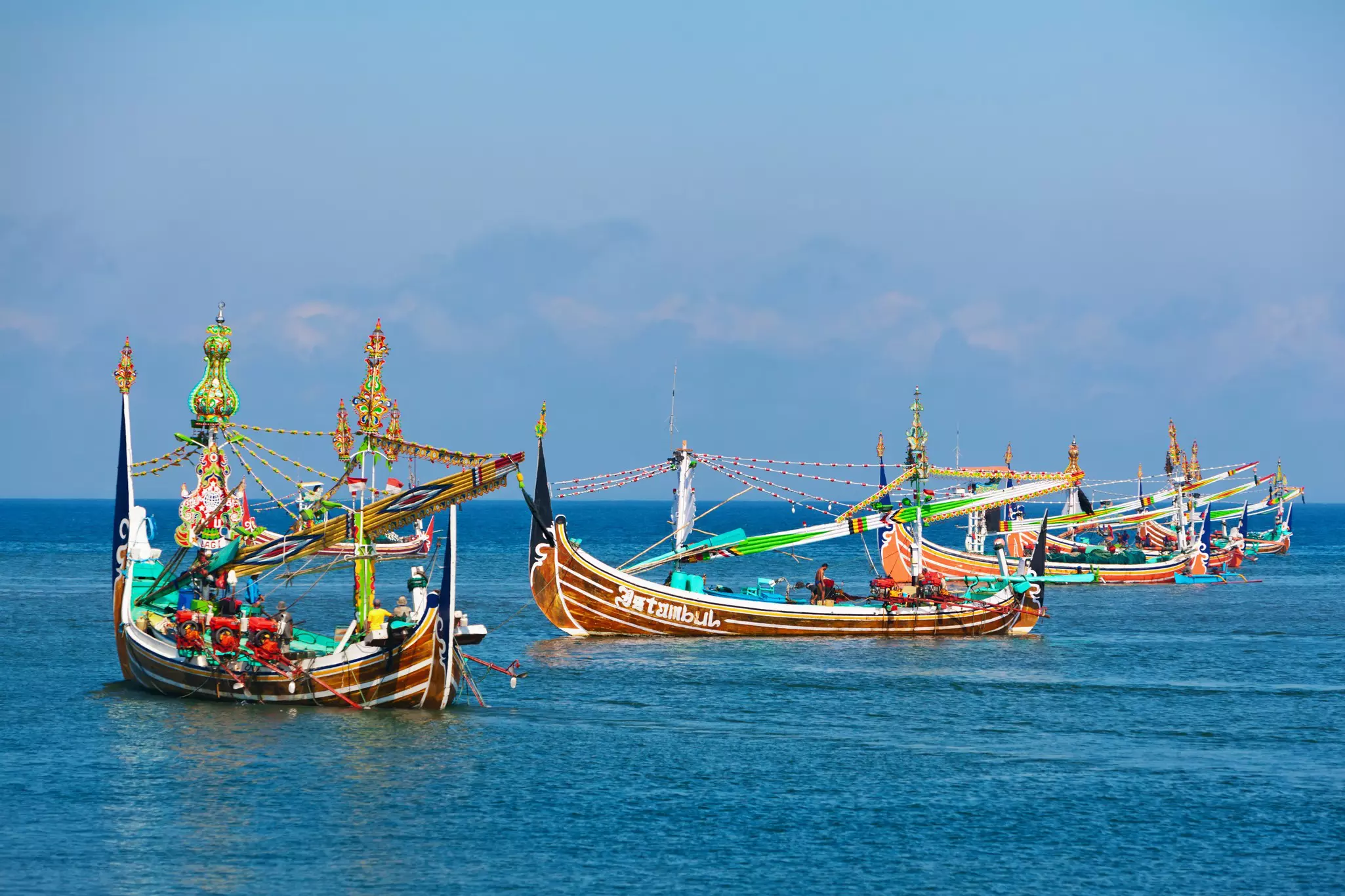 Brightly painted and decorated fishing boats are moored in the water.