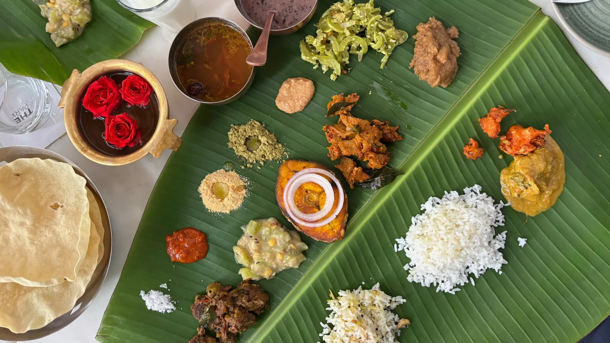 Small servings of rice, vegetables and sauces are served on a banana leaf.