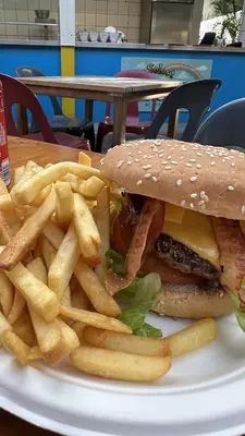 A cheeseburger on a sesame seed bun with fries on a white plate