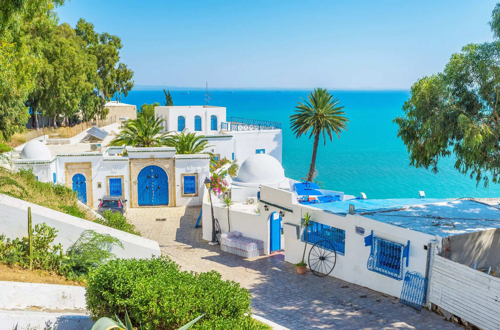 A whitewashed building with bright blue doors overlooking a brilliant blue sea.