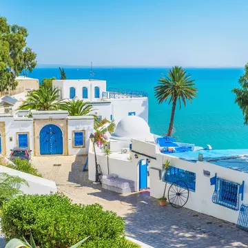 A whitewashed building with bright blue doors overlooking a brilliant blue sea.