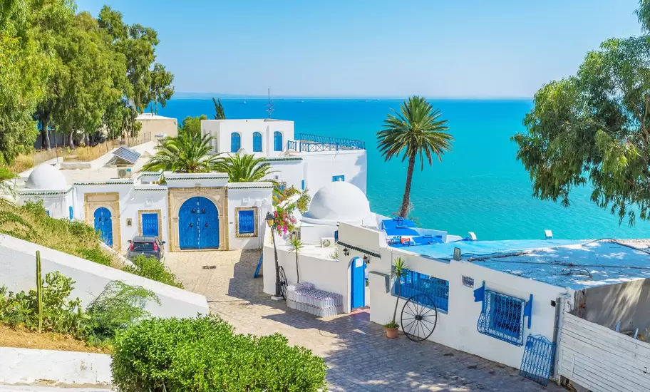 A whitewashed building with bright blue doors overlooking a brilliant blue sea.
