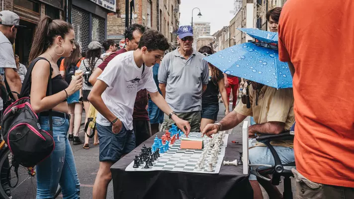 Man playing chess with passers by in Brick Lane, London.