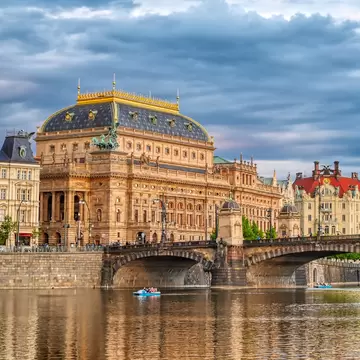 Wide exterior of the National Theatre located in Prague, Czech Republic on the Vltava River. Bridge and blue sky.