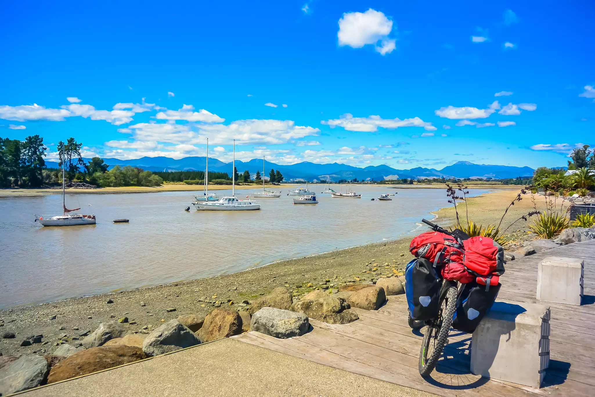 A bike fully loaded with packs and gear is parked next to a lake.