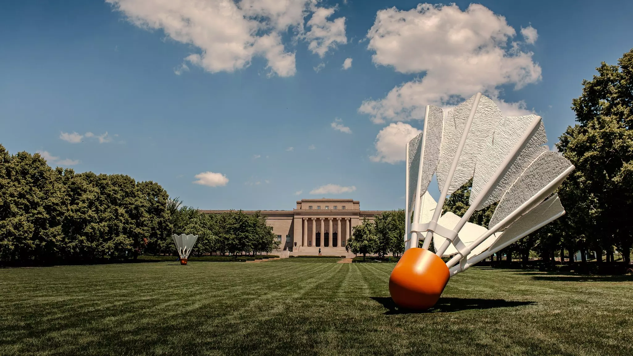 Two over-sized shuttlecock sculptures on the lawns outside a large art museum.