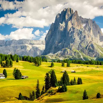 The dramatic Dolomite peaks, rising behind verdant Alpine pastureland. Creativaimage / Getty Images