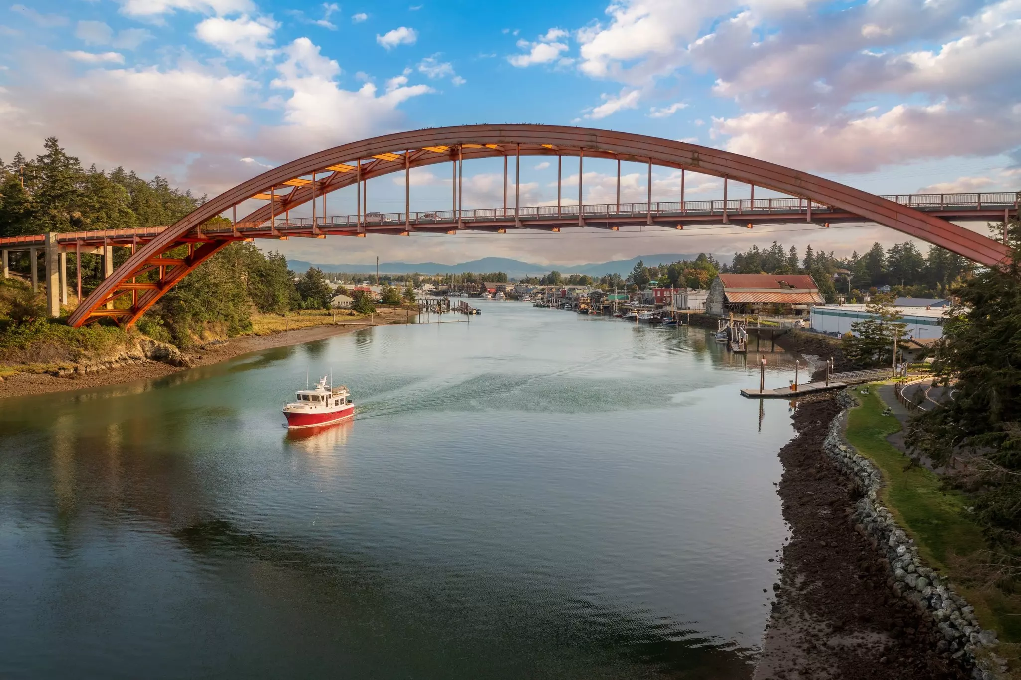 Historic Rainbow Bridge in the tourist town of La Conner, Washington with a boat passing underneath. The bridge connects the town to the island that is part of the Swinomish Reservation.