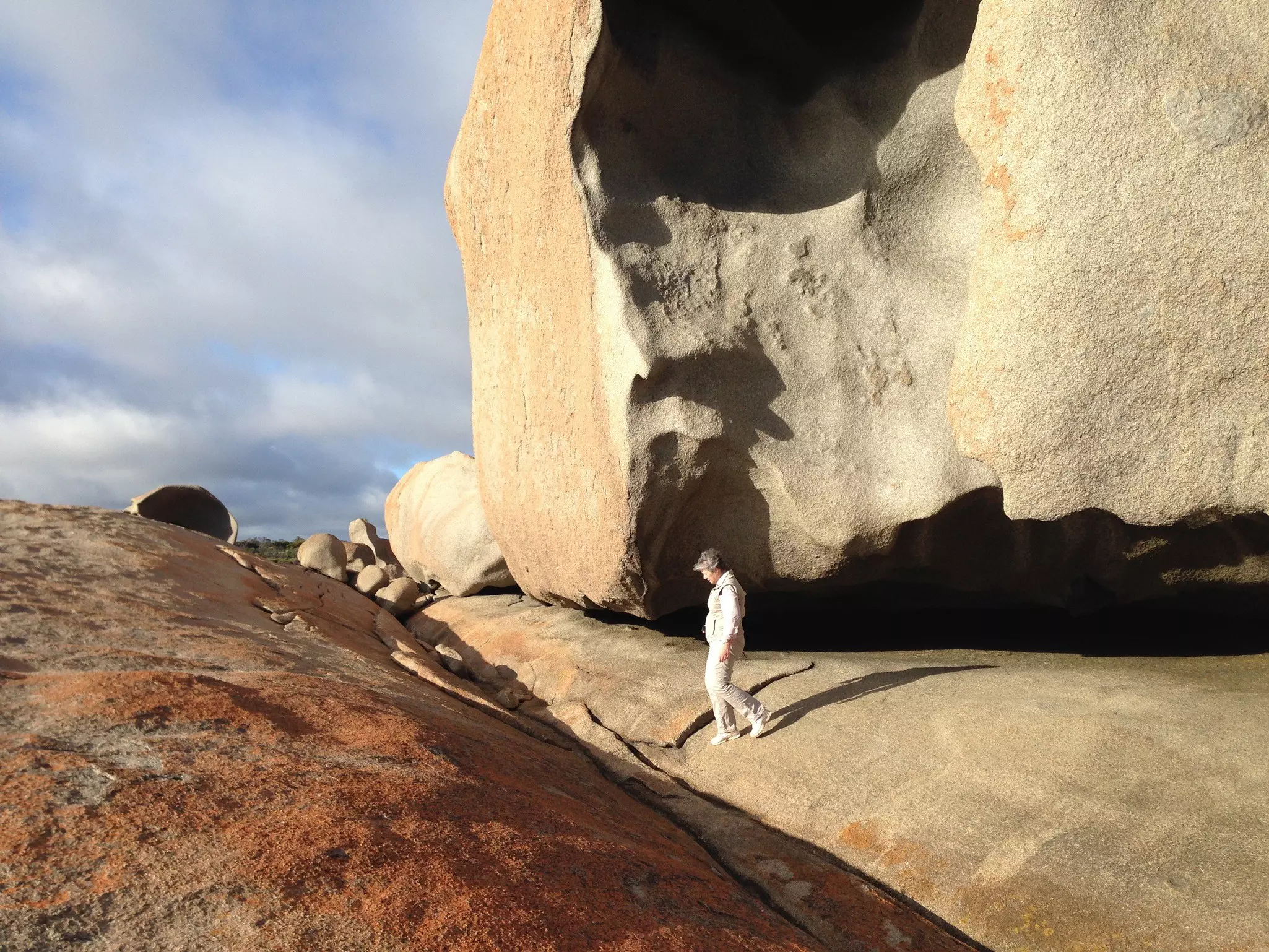 A woman in white walks over giant rock boulders in Australia