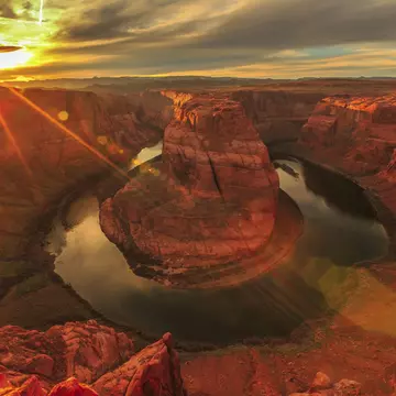 Horseshoe Bend during a vibrant sunset. 
508499104
Tall - High, Red, Journey, USA, Grand Canyon, Famous Place, National Park, North America, Curve, Rock - Object, Page - Arizona, Colorado River, River, Outdoors, Sunlight, 103626, Back Lit, Business Travel, Scenics - Nature, Horseshoe Bend - Colorado River, Sky, Cliff, Lake Powell, Ravine, Landscape - Scenery, Arizona, Extreme Terrain, Landscape, Grand Canyon National Park, Nature, Photography, Wilderness Area, Business Finance and Industry, Drinking Water, Horseshoe Bend, Red Rocks State Park - Arizona, Travel Destinations, Horizontal, Travel, Red Rocks, Hiking, No People, Glen Canyon National Recreation Area, Sunset, Reflective, Desert, Reflection, Tail Light, Canyon, Sunbeam, Lens Flare, Star Shape, Copy Space