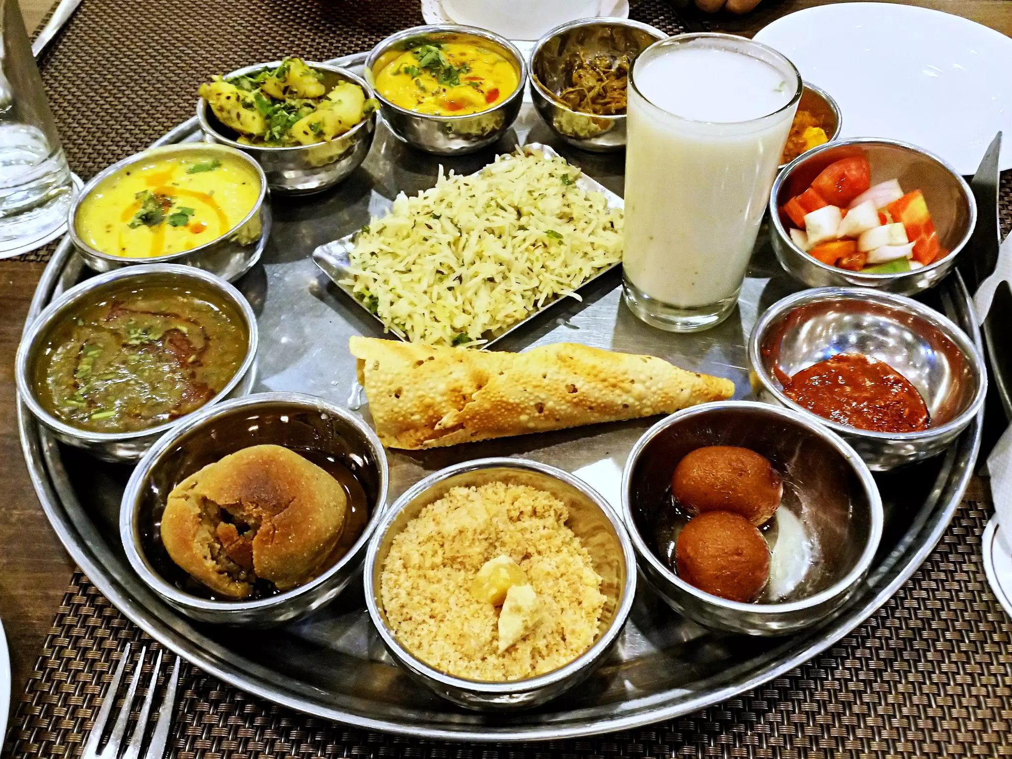 A thali (Indian-style metal plate) is packed with small servings of various foods.