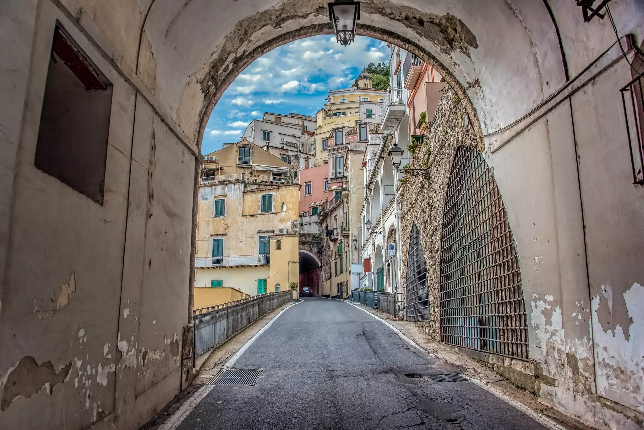 A car winds up a narrow road between tightly packed buildings