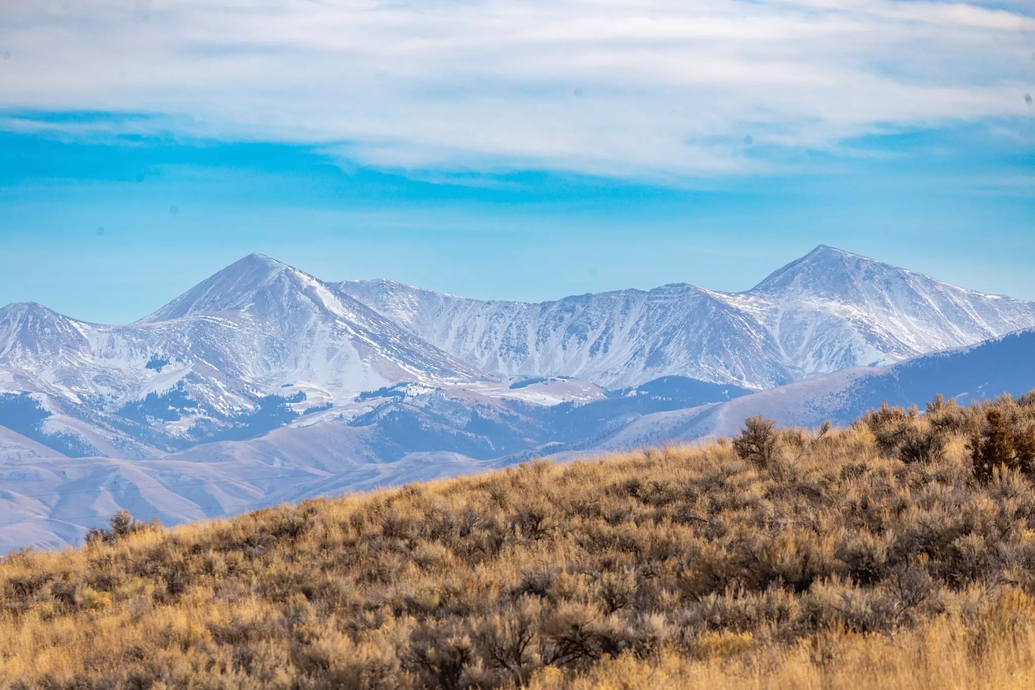 A grassy slope frames the mountains in Montana in late fall. 