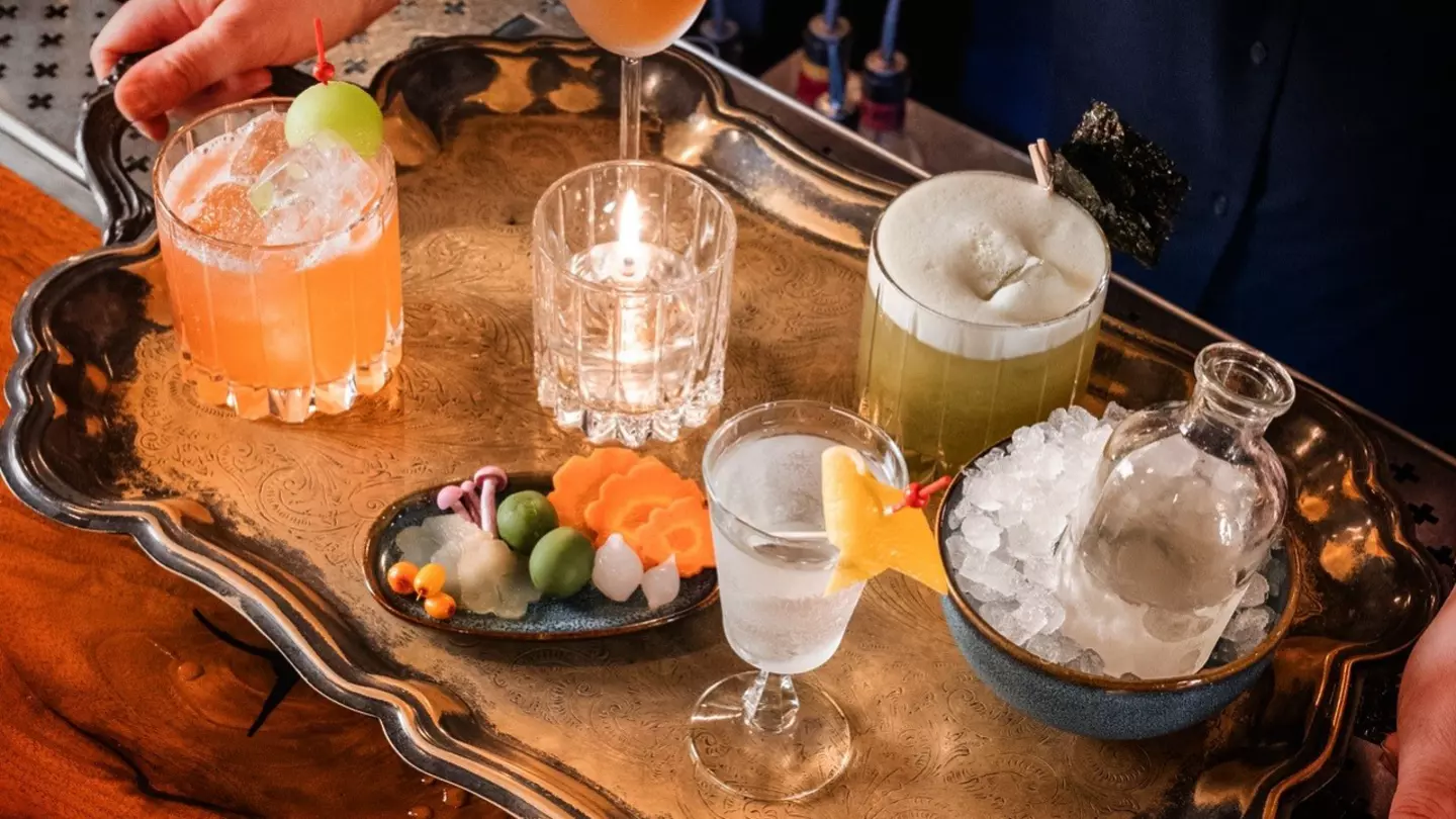 A silver tray loaded with colorful drinks and a bowl of ice.