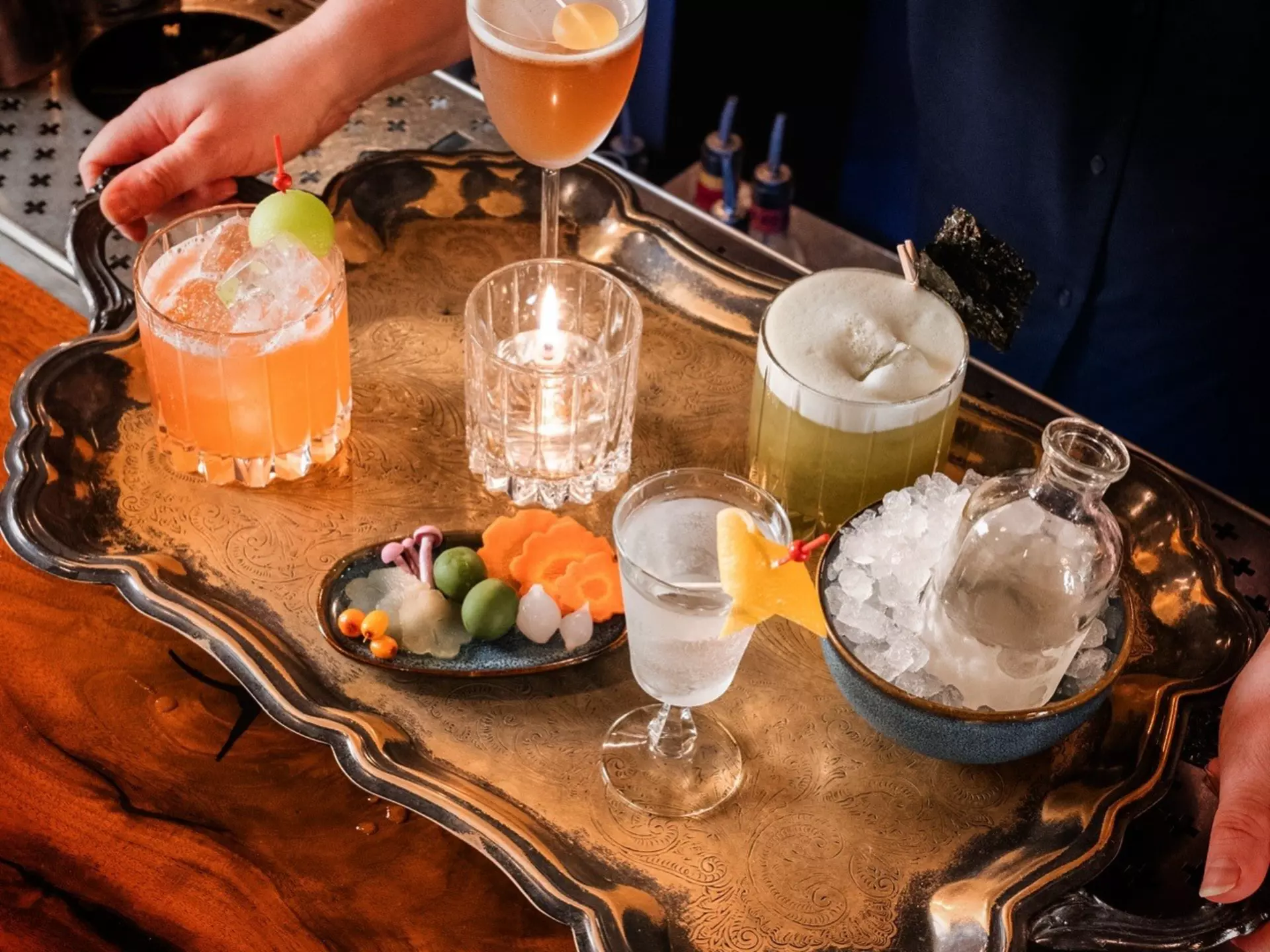 A silver tray loaded with colorful drinks and a bowl of ice.