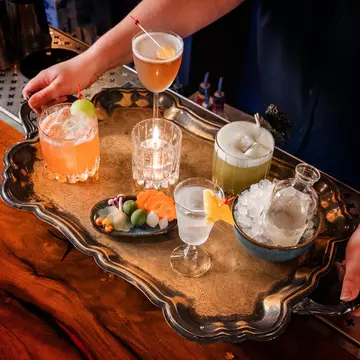 A silver tray loaded with colorful drinks and a bowl of ice.