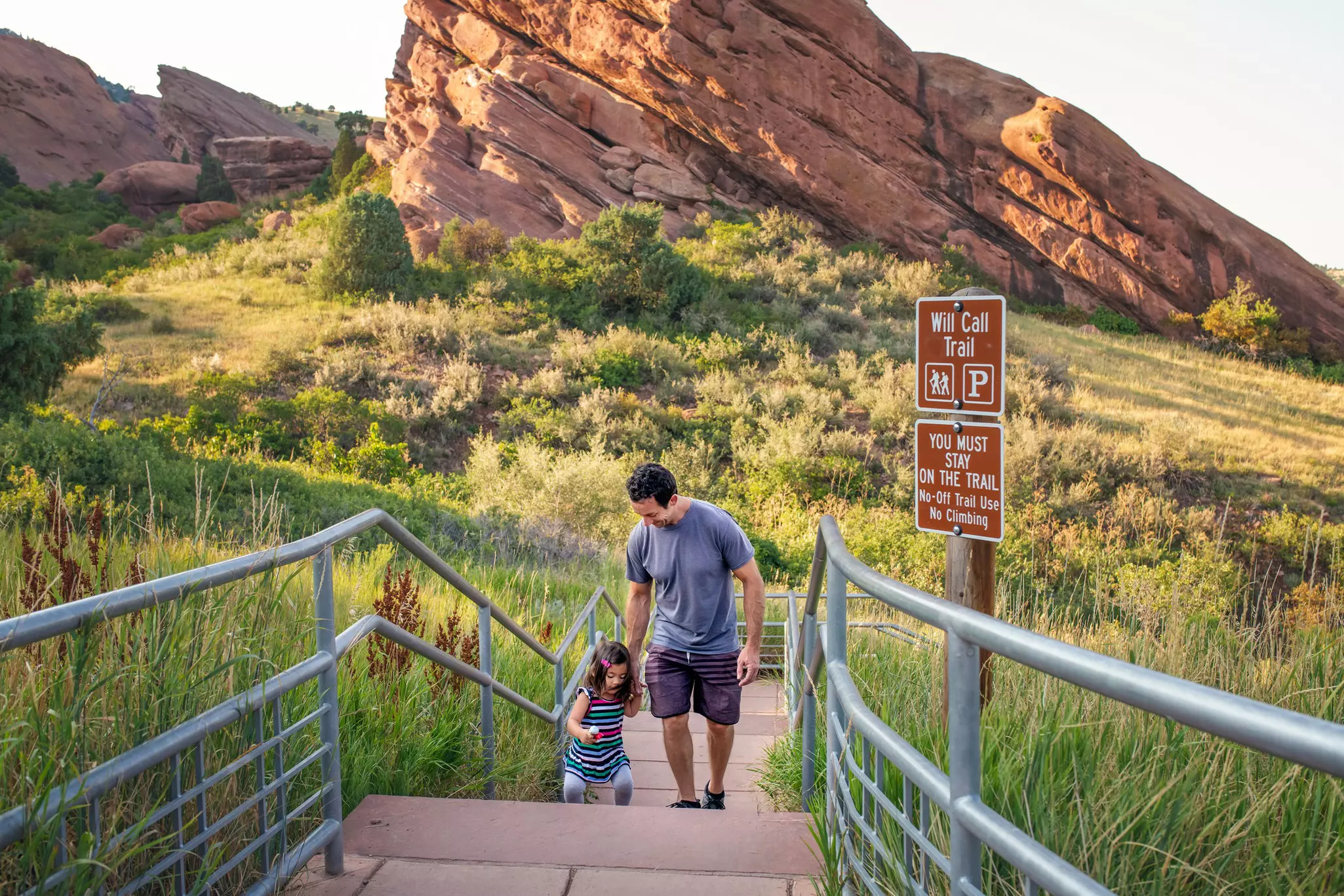 A father helping his toddler up the stairs at Red Rock Park, Colorado.