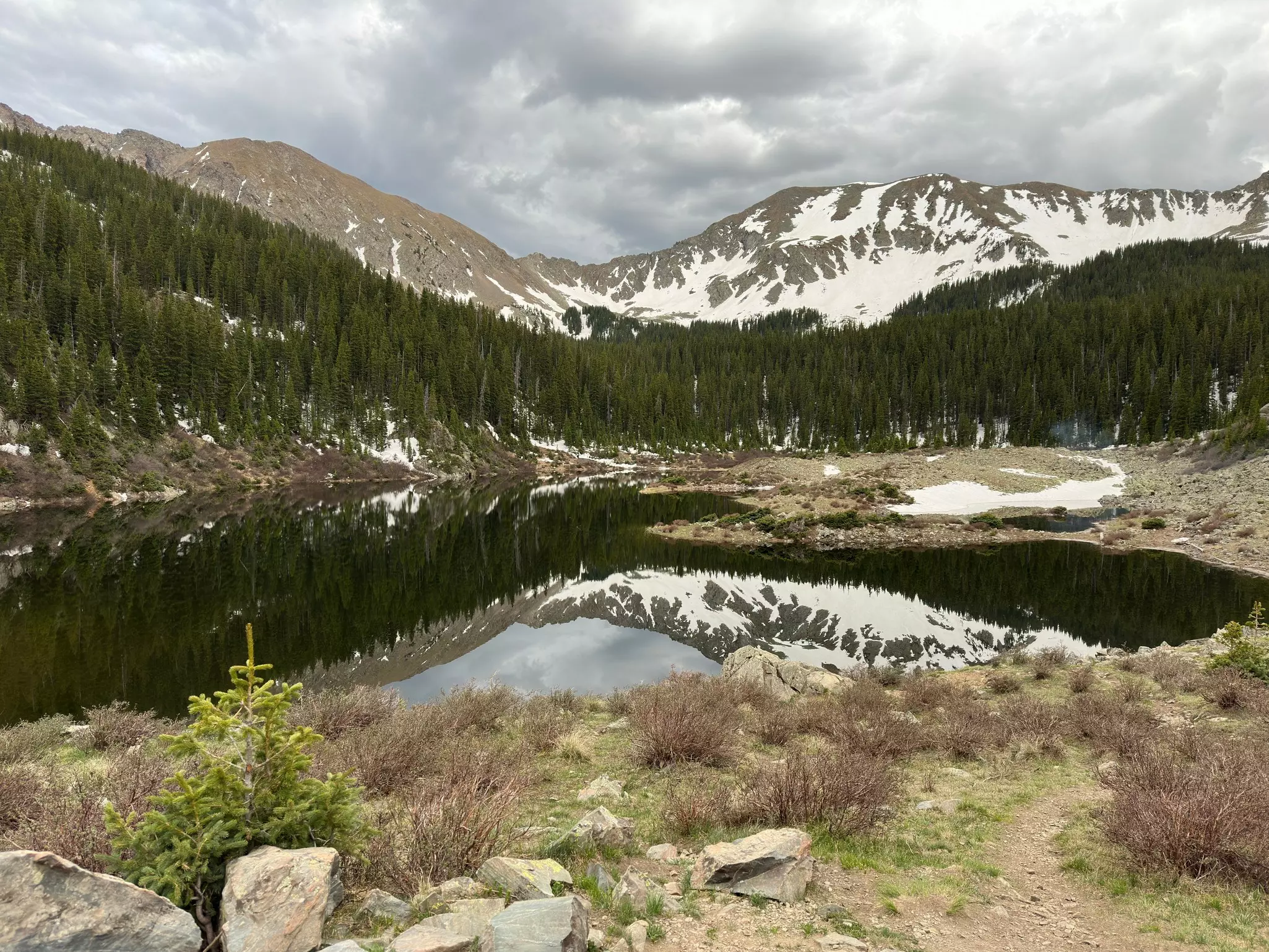 A lake with snow-dusted mountains in the distance on a cloudy day.