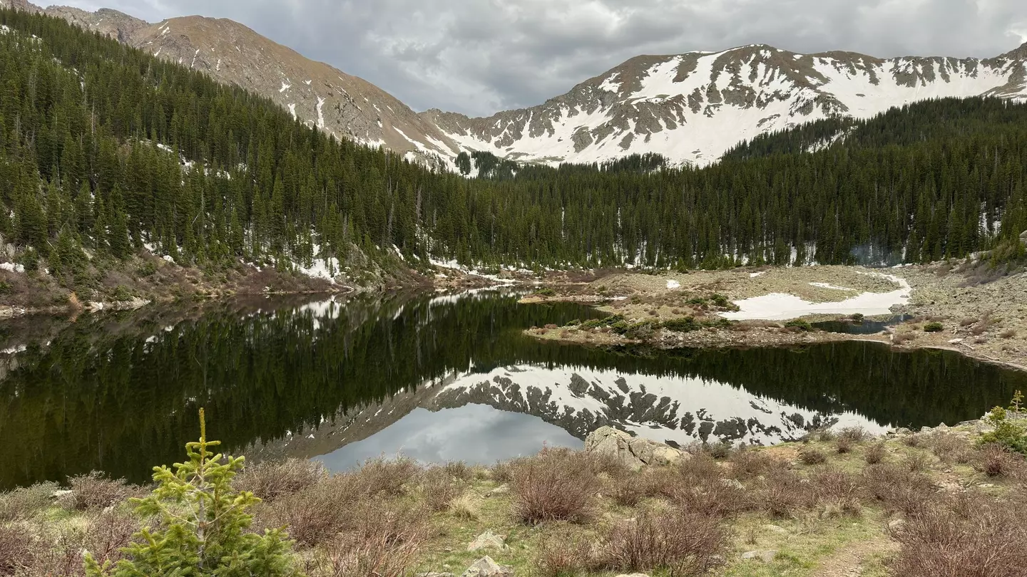 A lake with snow-dusted mountains in the distance on a cloudy day.