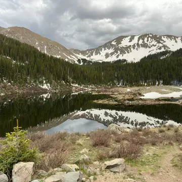 A lake with snow-dusted mountains in the distance on a cloudy day.