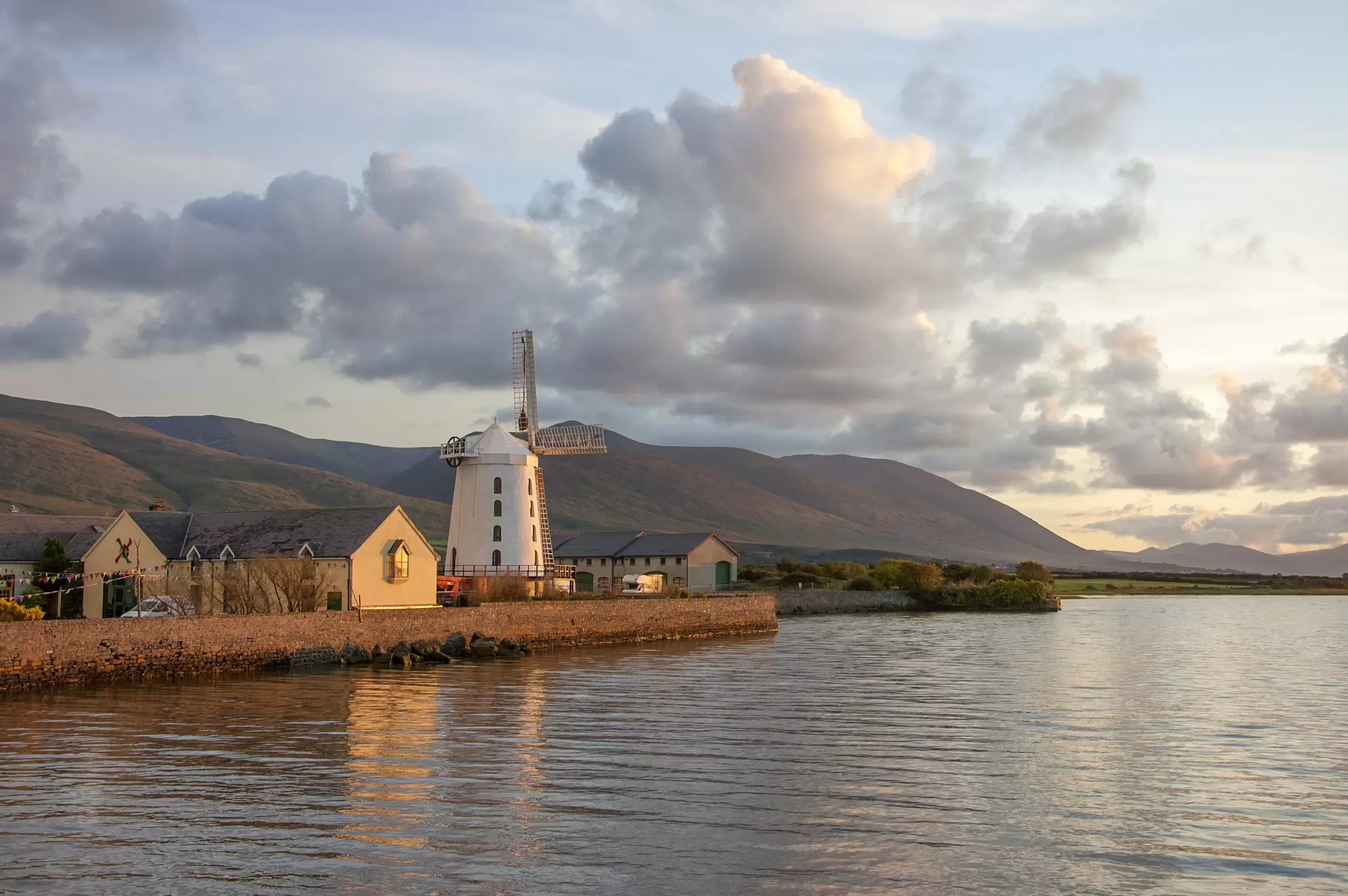 The Blennerville Windmill next to the water in Tralee as the sunsets on a cloudy day.